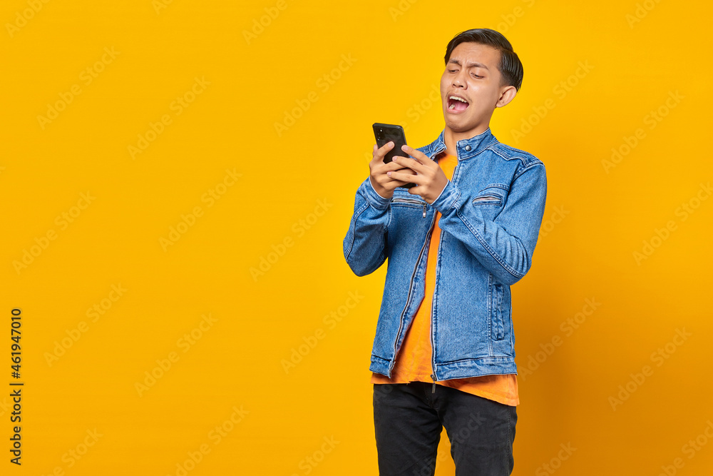 Shocked Asian young man looking at message on smartphone Shocked Asian young man looking at message on smartphone