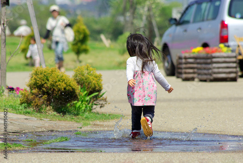 公園の水たまりを走り抜ける女児