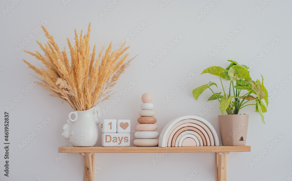 Obraz premium Wooden shelf with stylish children's wooden toys. Pyramid, rainbow and white wooden cubes with the inscription one day. Home comfort concept.