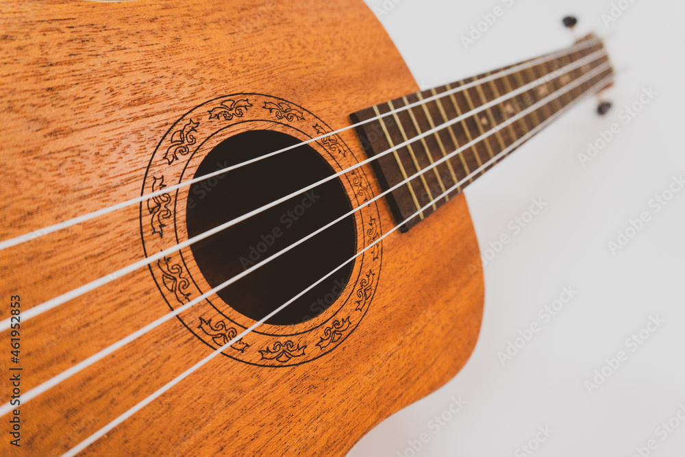 Close up of brown Ukulele on white background. Ukulele strings, saddle, soundhole, ukulele body, neck, fretboard. Close up of brown Ukulele on white background. Ukulele strings, saddle, soundhole, ukulele body, neck, fretboard.