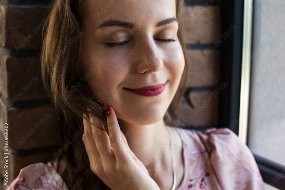 Beautiful young woman in pink dress resting on the windowsill. Portrait of happy smiling girl sits on the stained glass window at industrial loft wooden brick style interior. Leisure concept. Beautiful young woman in pink dress resting on the windowsill. Portrait of happy smiling girl sits on the stained glass window at industrial loft wooden brick style interior. Leisure concept.