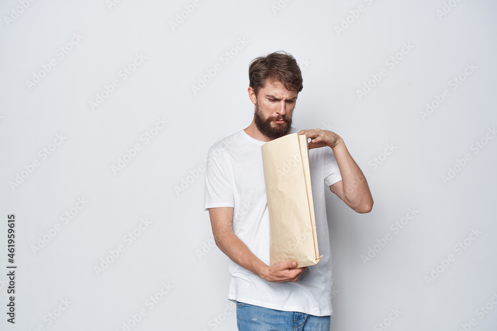 Fototapeta premium bearded man in a white t-shirt with a package in his hands emotions mockup
