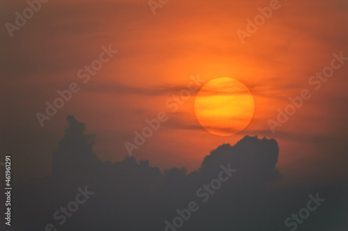 Sun disk through the clouds at sunset above the horizon.