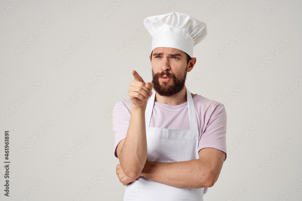 Cheerful male chef in uniform cooking food kitchen light background Cheerful male chef in uniform cooking food kitchen light background