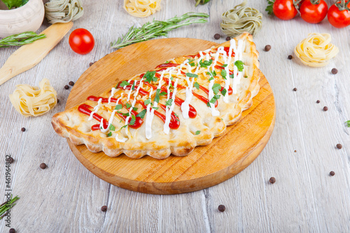 pizza calzone with red and white sauce on a wooden board