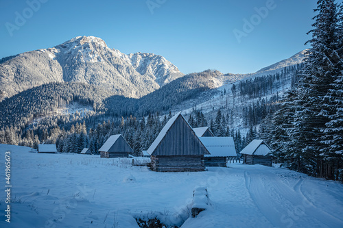 Polana Chochołowska in early morning, Western Tatra Mountains, Poland. Old abandoned agricultural buildings in snow. Selective focus on the exterior of buildings, blurred background. photo