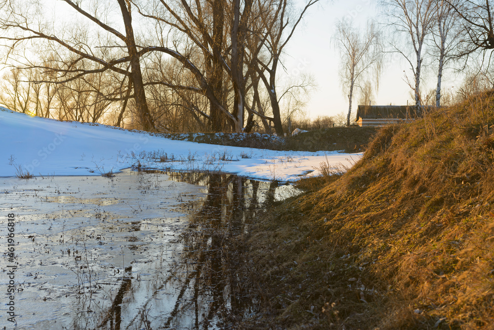 Spring evening landscape with melting snow in a ravine with trees Spring evening landscape with melting snow in a ravine with trees