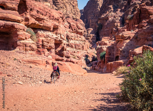 Arab woman riding a donkey on the Ed-Deir Trail (monastery trail) in the ancient city of Petra, Jordan.