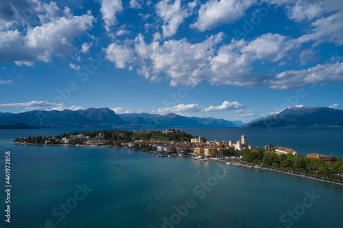 Aerial view of the island of Sirmione. Sirmione, Lake Garda, Italy. Panorama of Lake Garda. Peninsula on a mountain lake in the background of the alps. Castle on the water in Italy. © Berg