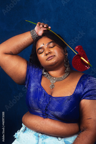 portrait of dark skinned Indian woman from Malaysia against a dark blue background, with flower photo