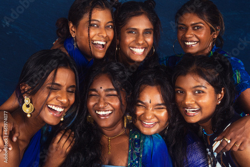 group portraits of dark skinned Indian women from Malaysia against a dark blue background, laughing