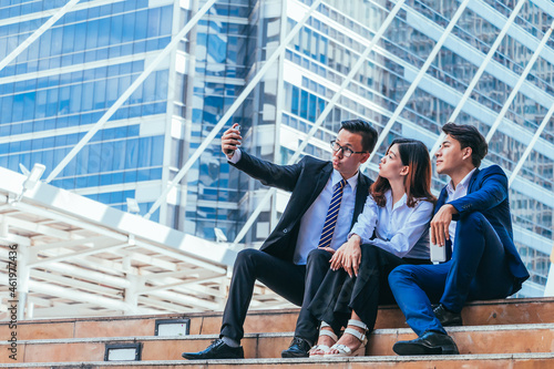 Young business team sitting on stairs and selfie with cityscape background.