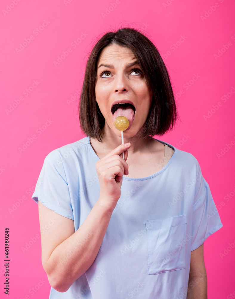 Young woman with sensitive teeth eating sweet lollipop on color background Young woman with sensitive teeth eating sweet lollipop on color background