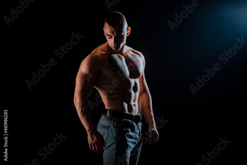 Healthy muscular young man on a dark background