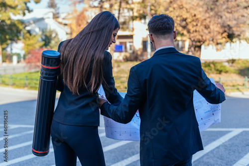 Papier peint Backview of suited male and female architects looking together at a building blu