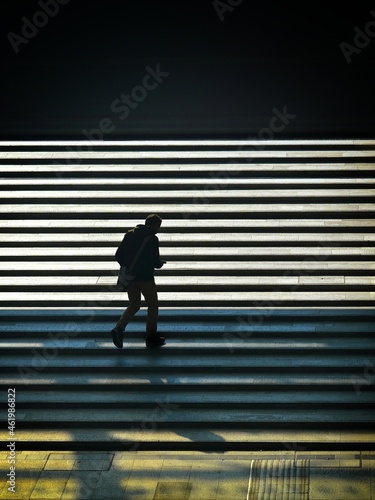 lonely person silhouette walking upstairs under bright backlit sunlight