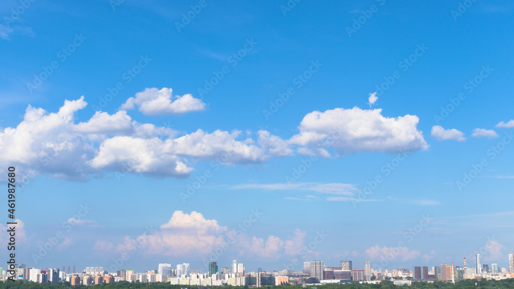 Bright background with blue sky and white clouds and urban Moscow buildings on the horizon