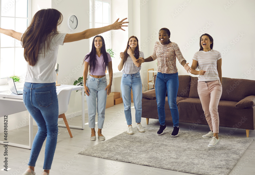 Happy ecstatic young woman jumping for joy while celebrating her success with her best friends. Group of excited multicultural ladies congratulating their friend on happy event in her life Happy ecstatic young woman jumping for joy while celebrating her success with her best friends. Group of excited multicultural ladies congratulating their friend on happy event in her life