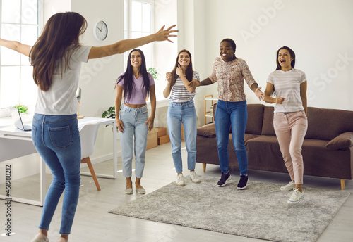 Happy ecstatic young woman jumping for joy while celebrating her success with her best friends. Group of excited multicultural ladies congratulating their friend on happy event in her life