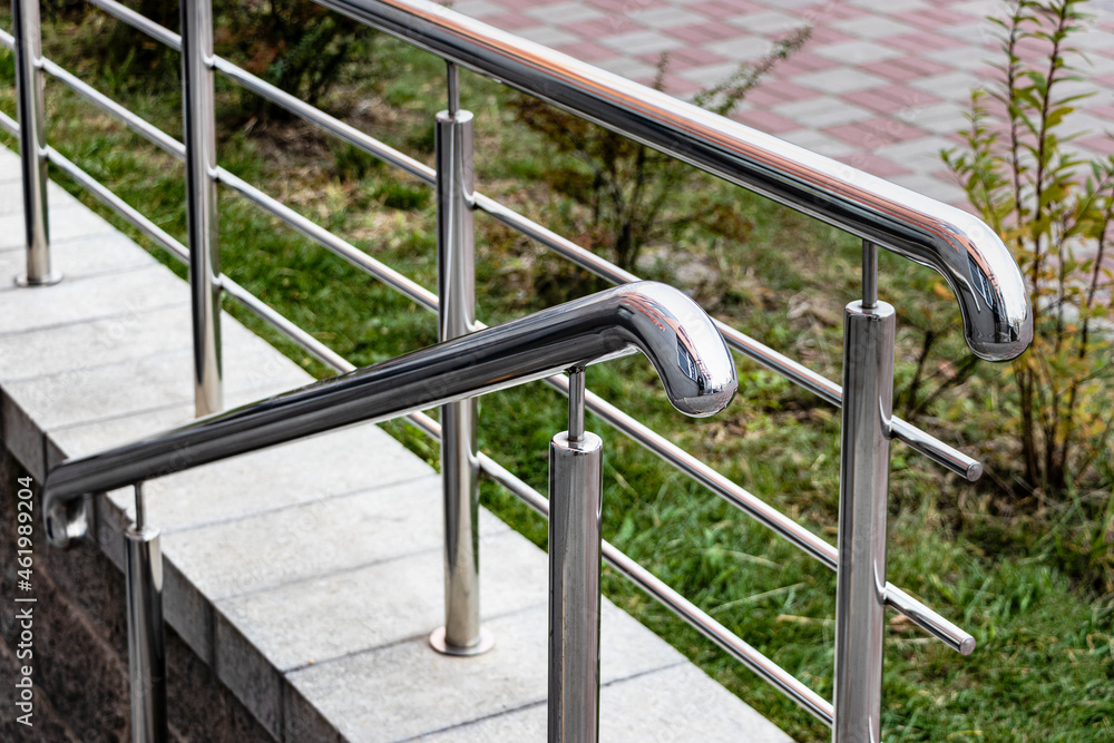 A ramp and metal railings at the entrance to the residential building for the convenience of people with disabilities and the elderly. A ramp and metal railings at the entrance to the residential building for the convenience of people with disabilities and the elderly.