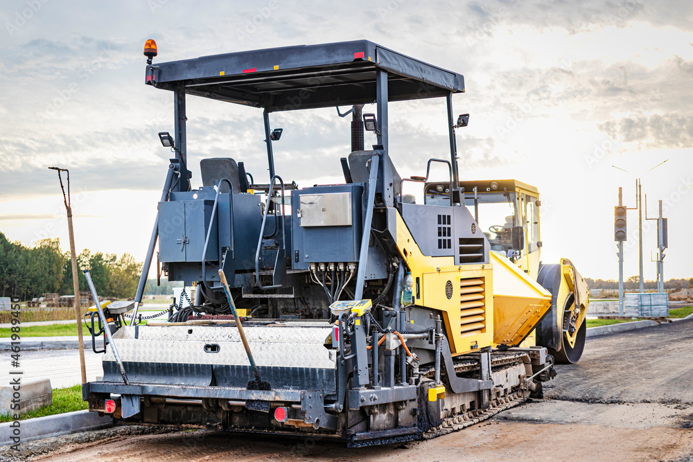 Asphalt paving equipment. Asphalt paver and heavy vibratory roller. Construction of new roads and road junctions. Heavy construction industrial machinery. Asphalt paving equipment. Asphalt paver and heavy vibratory roller. Construction of new roads and road junctions. Heavy construction industrial machinery.
