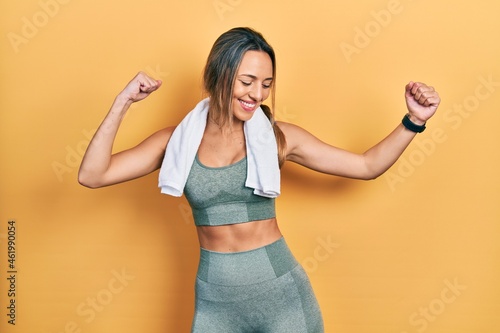 Beautiful hispanic woman wearing sportswear and towel dancing happy and cheerful, smiling moving casual and confident listening to music
