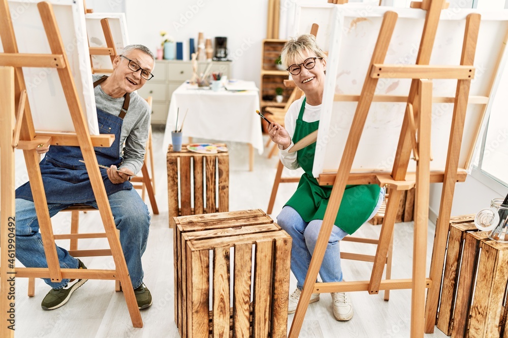 Two middle age artist smiling happy painting at art studio.