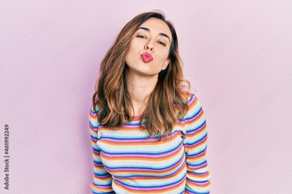 Young hispanic girl wearing casual clothes looking at the camera blowing a kiss on air being lovely and sexy. love expression. Young hispanic girl wearing casual clothes looking at the camera blowing a kiss on air being lovely and sexy. love expression.