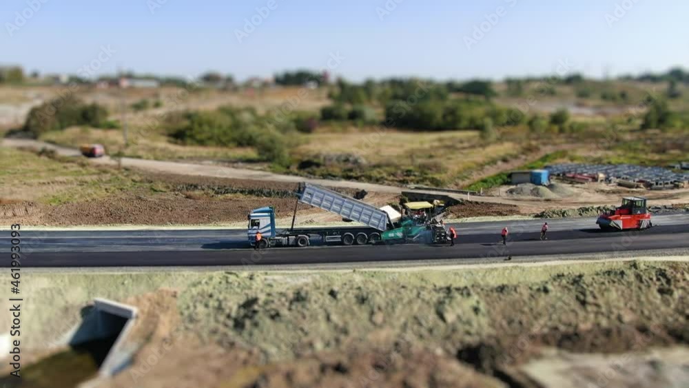 Aerial viev: Making new asphalt at road construction. Paver or paving machine lay bitumen. Rollers levele and compact new asphalt. Road surface repair. Construction of new road. Tilt-shift effect Aerial viev: Making new asphalt at road construction. Paver or paving machine lay bitumen. Rollers levele and compact new asphalt. Road surface repair. Construction of new road. Tilt-shift effect