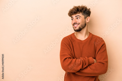Young arab man isolated on beige background smiling confident with crossed arms. © Asier