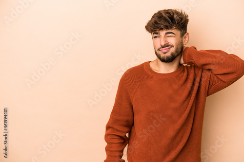 Young arab man isolated on beige background touching back of head, thinking and making a choice. © Asier