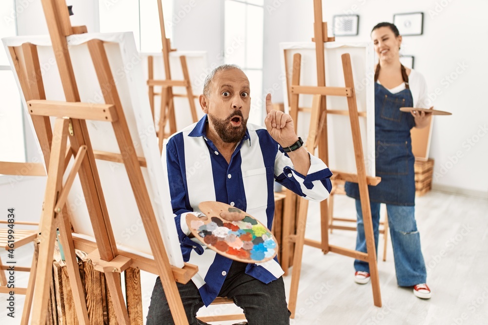 Senior artist man at art studio pointing finger up with successful idea. exited and happy. number one. Senior artist man at art studio pointing finger up with successful idea. exited and happy. number one.