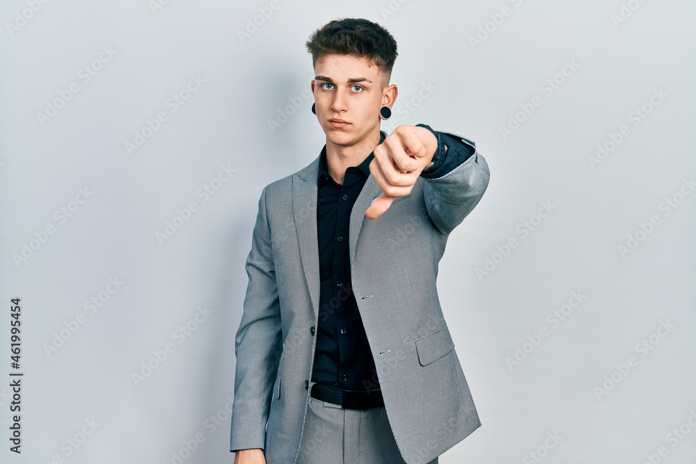 Young caucasian boy with ears dilation wearing business jacket looking unhappy and angry showing rejection and negative with thumbs down gesture. bad expression. Young caucasian boy with ears dilation wearing business jacket looking unhappy and angry showing rejection and negative with thumbs down gesture. bad expression.
