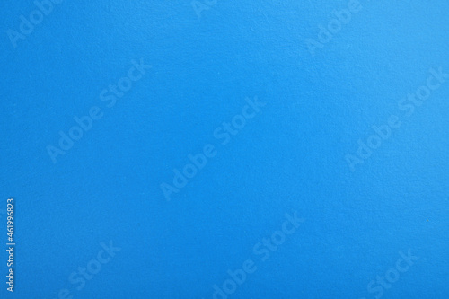 Abstract blue glossy paper texture background or backdrop. Blank wrapping paper or shiny cardboard for a decorative design element. Grainy surface.