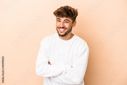 Young arab man isolated on beige background laughing and having fun.