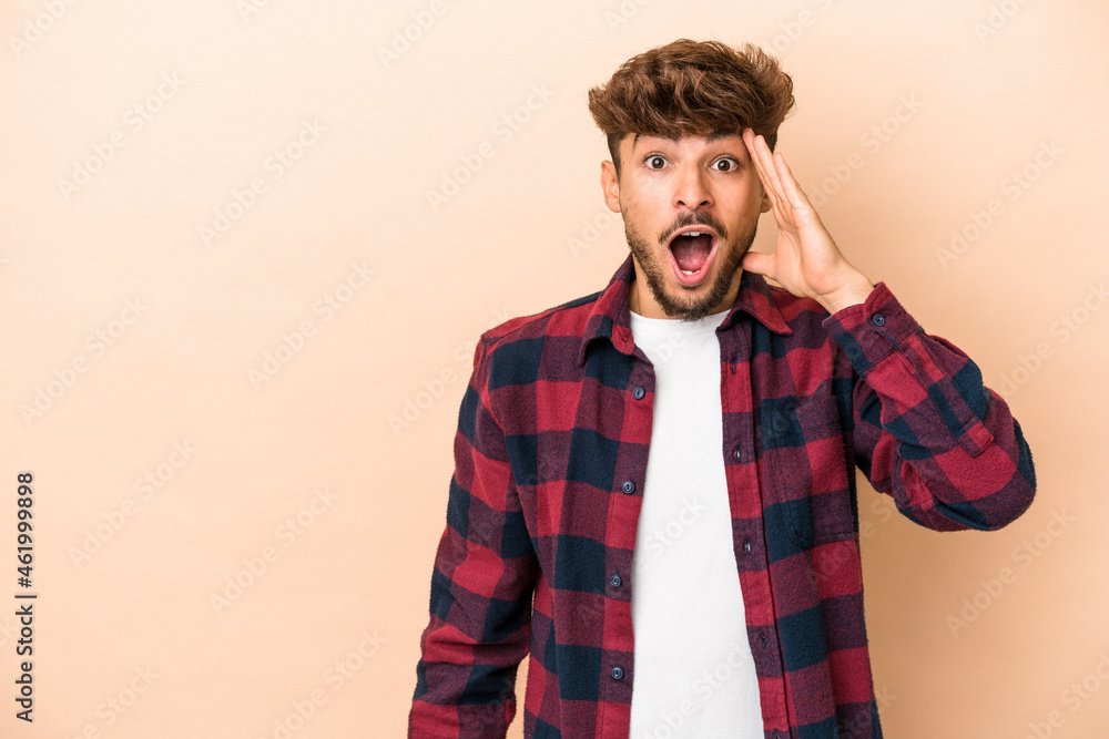 Young arab man isolated on beige background shouts loud, keeps eyes opened and hands tense. Young arab man isolated on beige background shouts loud, keeps eyes opened and hands tense.