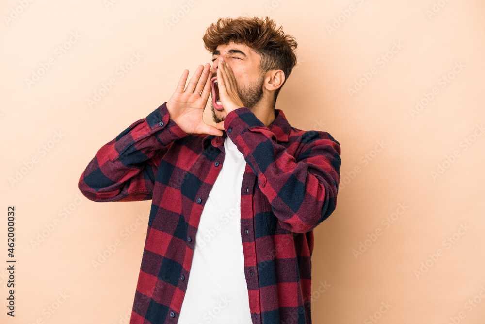 Young arab man isolated on beige background shouting excited to front. Young arab man isolated on beige background shouting excited to front.