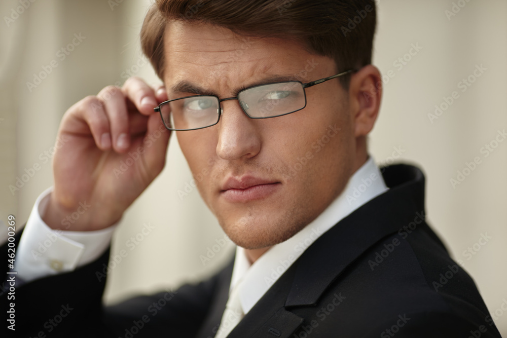 Closeup portrait of a handsome businessman in eyeglasses and black suit and white tie and shirt. Horizontal view.