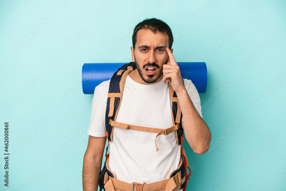 Young caucasian hiker man isolated on blue background showing a disappointment gesture with forefinger. Young caucasian hiker man isolated on blue background showing a disappointment gesture with forefinger.