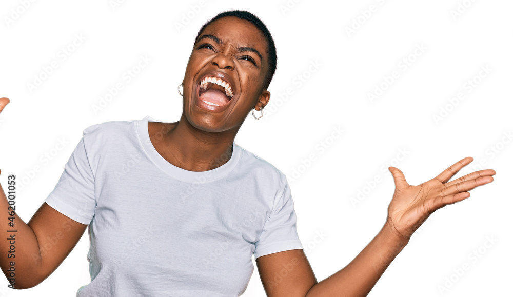 Young african american woman wearing casual white t shirt celebrating mad and crazy for success with arms raised and closed eyes screaming excited. winner concept Young african american woman wearing casual white t shirt celebrating mad and crazy for success with arms raised and closed eyes screaming excited. winner concept