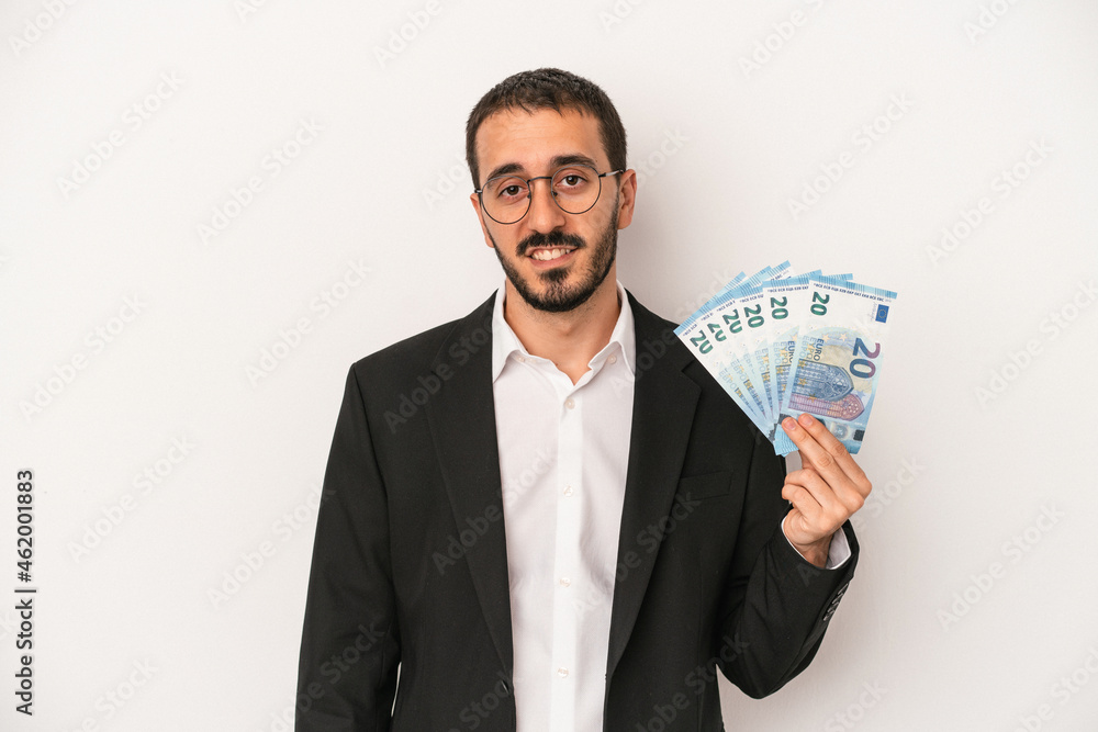 Young caucasian business man holding banknotes isolated on white background happy, smiling and cheerful. Young caucasian business man holding banknotes isolated on white background happy, smiling and cheerful.