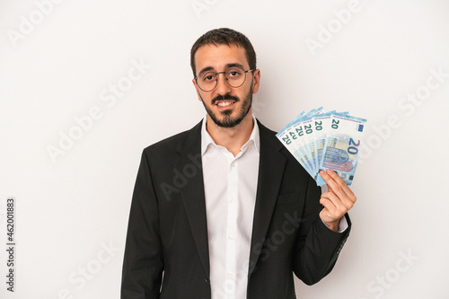 Young caucasian business man holding banknotes isolated on white background happy, smiling and cheerful.
