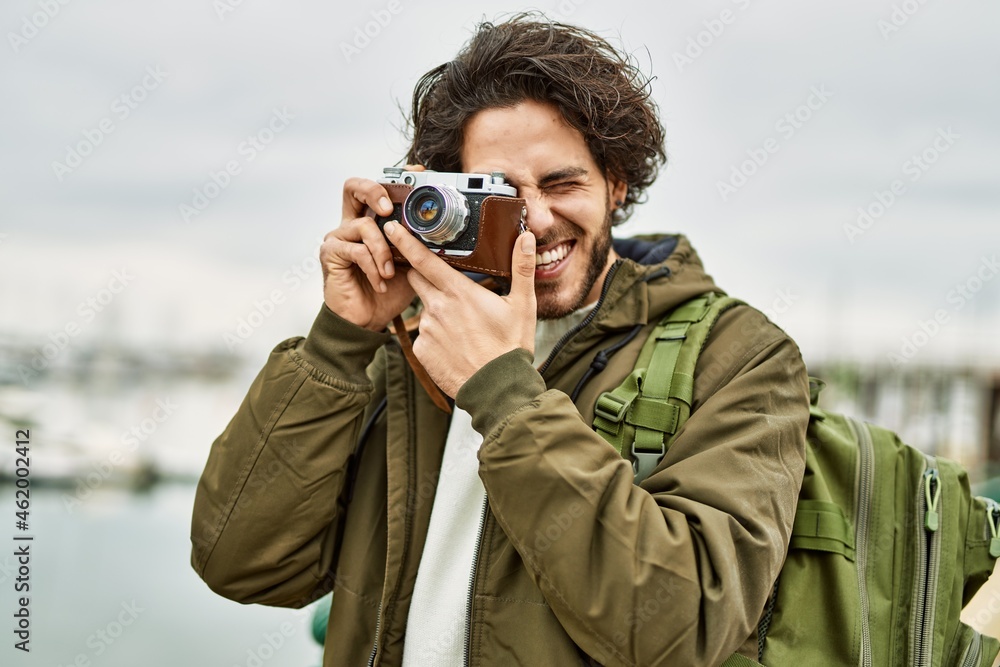 Obraz premium Handsome hispanic man using vintage camera by marina port