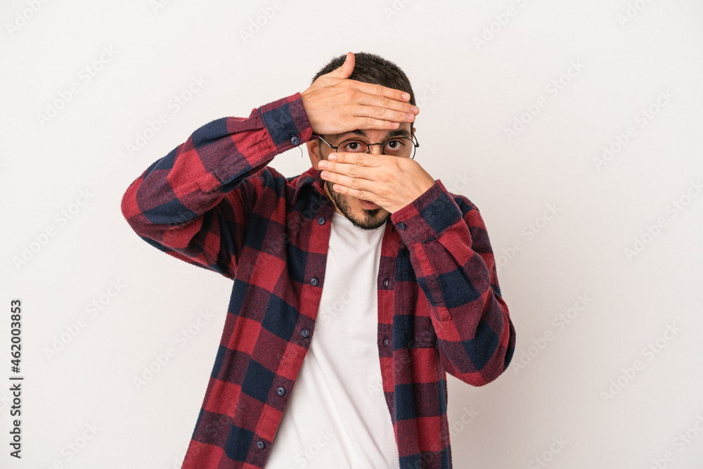 Young caucasian man isolated on white background blink at the camera through fingers, embarrassed covering face. Young caucasian man isolated on white background blink at the camera through fingers, embarrassed covering face.