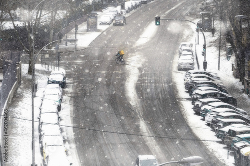 Food delivery man on a bicycle working under the snow in Madrid. photo