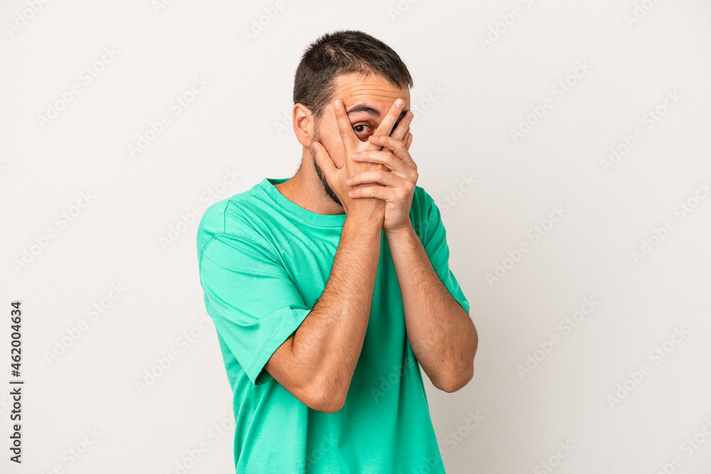 Young caucasian man isolated on white background blink through fingers frightened and nervous. Young caucasian man isolated on white background blink through fingers frightened and nervous.