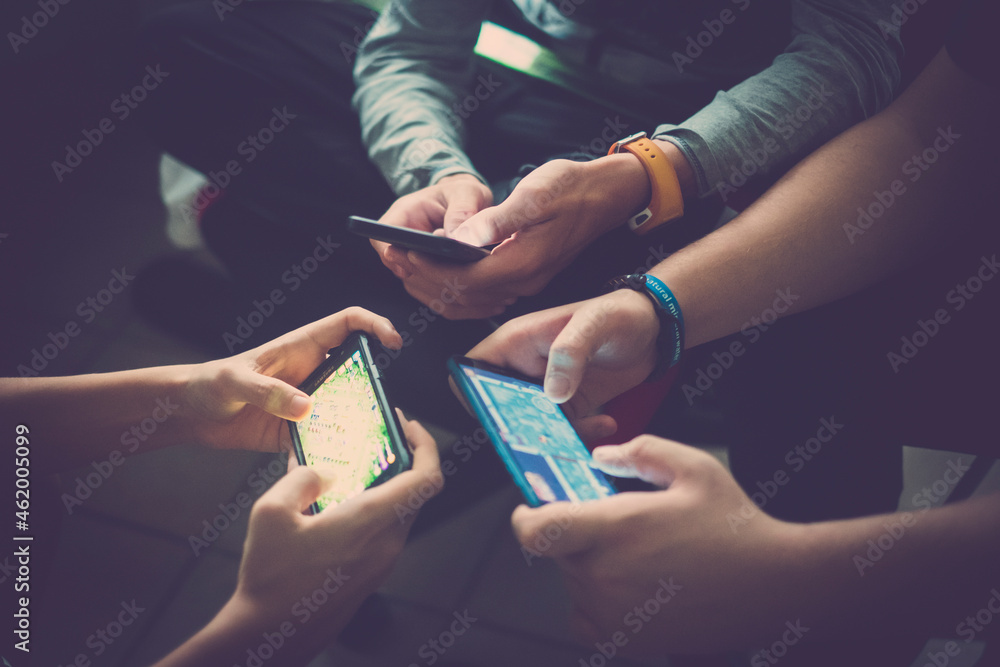 Close up of hands of three teenager friends addicted to technology playing with smartphones together. Teenage boys using mobile phones for social networking and leisure activities. - obrazy, fototapety, plakaty 