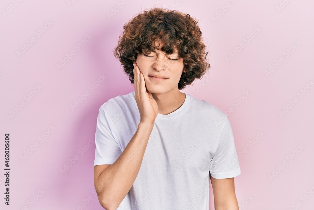 Handsome young man wearing casual white t shirt touching mouth with hand with painful expression because of toothache or dental illness on teeth. dentist Handsome young man wearing casual white t shirt touching mouth with hand with painful expression because of toothache or dental illness on teeth. dentist