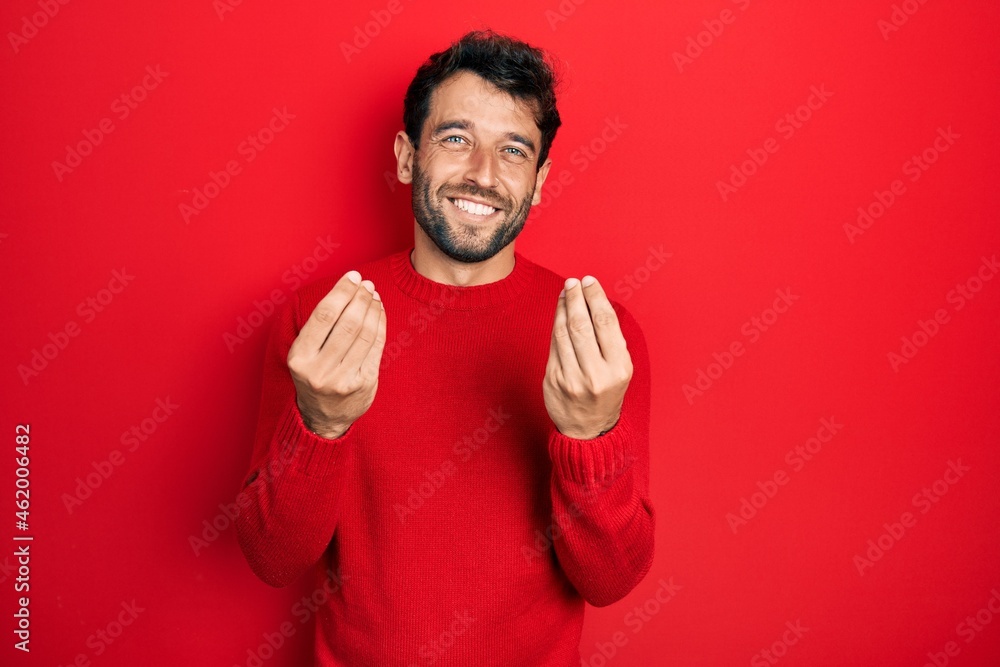 Handsome man with beard wearing casual red sweater doing money gesture with hands, asking for salary payment, millionaire business Handsome man with beard wearing casual red sweater doing money gesture with hands, asking for salary payment, millionaire business
