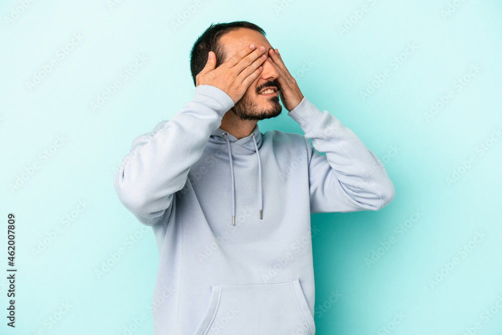Young caucasian man isolated on blue background afraid covering eyes with hands. Young caucasian man isolated on blue background afraid covering eyes with hands.